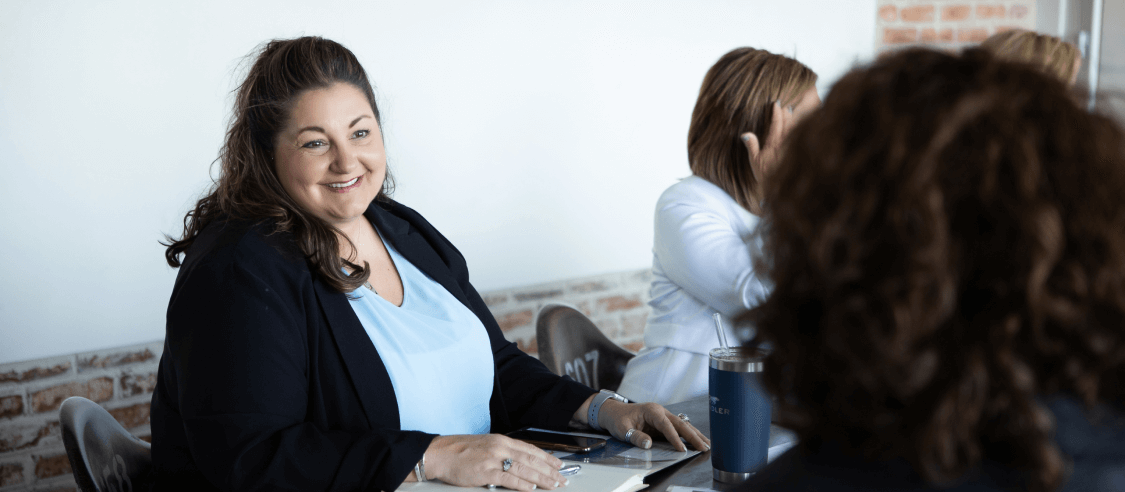 Women sitting at desks talking about careers at Team Handler.