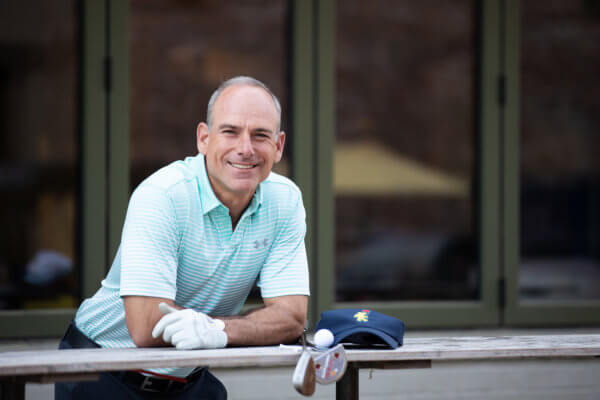 Eric Handler in golf gear leaning over railing.