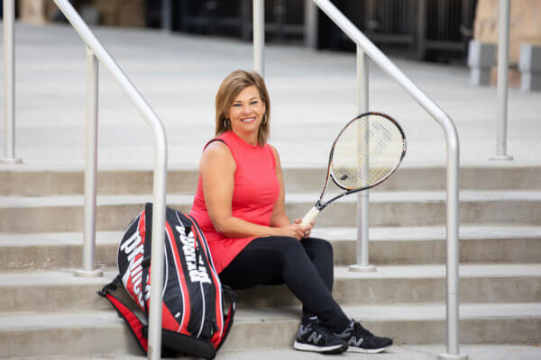 Laura Lloyd sitting on the stairs with tennis racket