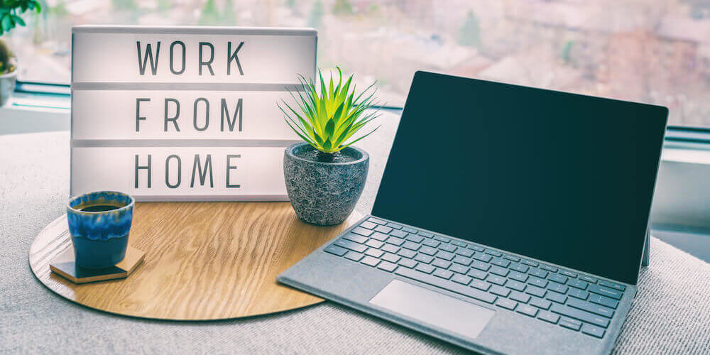 Desk with laptop, coffee mug, plant, and sign that reads Work From Home