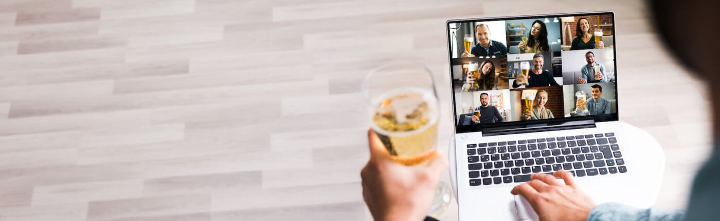 Person holding beer on Zoom video chat with team