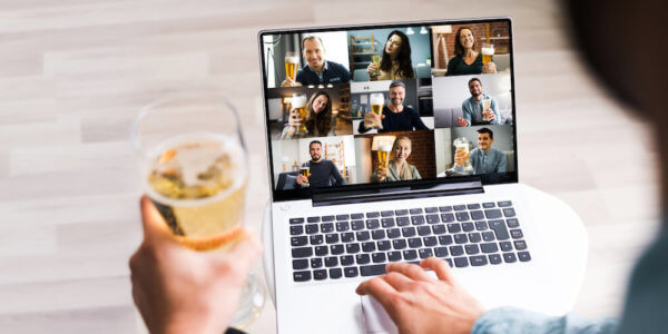 Person holding beer on Zoom video chat with team