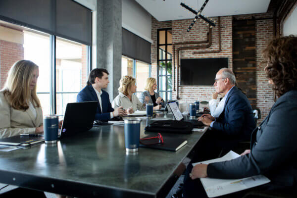 Handler team sitting around conference table discussing questions leaders should ask