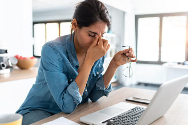 Woman looking stressed trying to avoid burnout with her hands on her head looking at her laptop