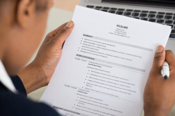 Photo of man holding resume looking for lies and inconsistencies in resumes